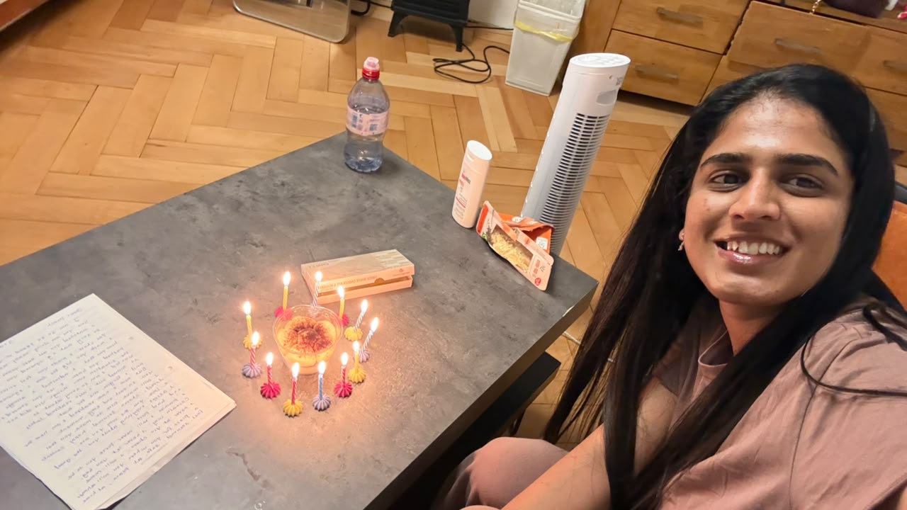 A small cake ringed with lit candles on a table at midnight, a handwritten note beside it.